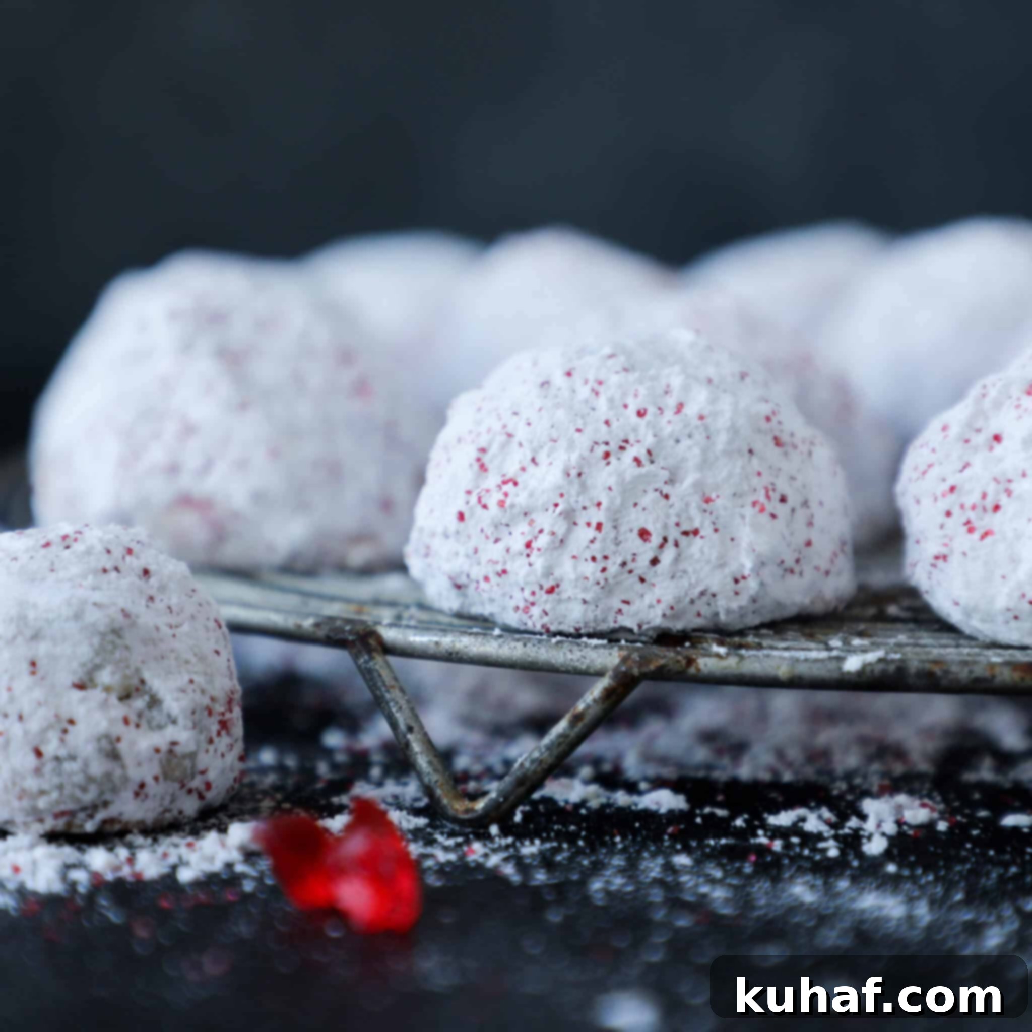 Cherry Pistachio Snowball Cookies Cherry: A close-up of a snowball cookie with visible chopped cherry pieces.