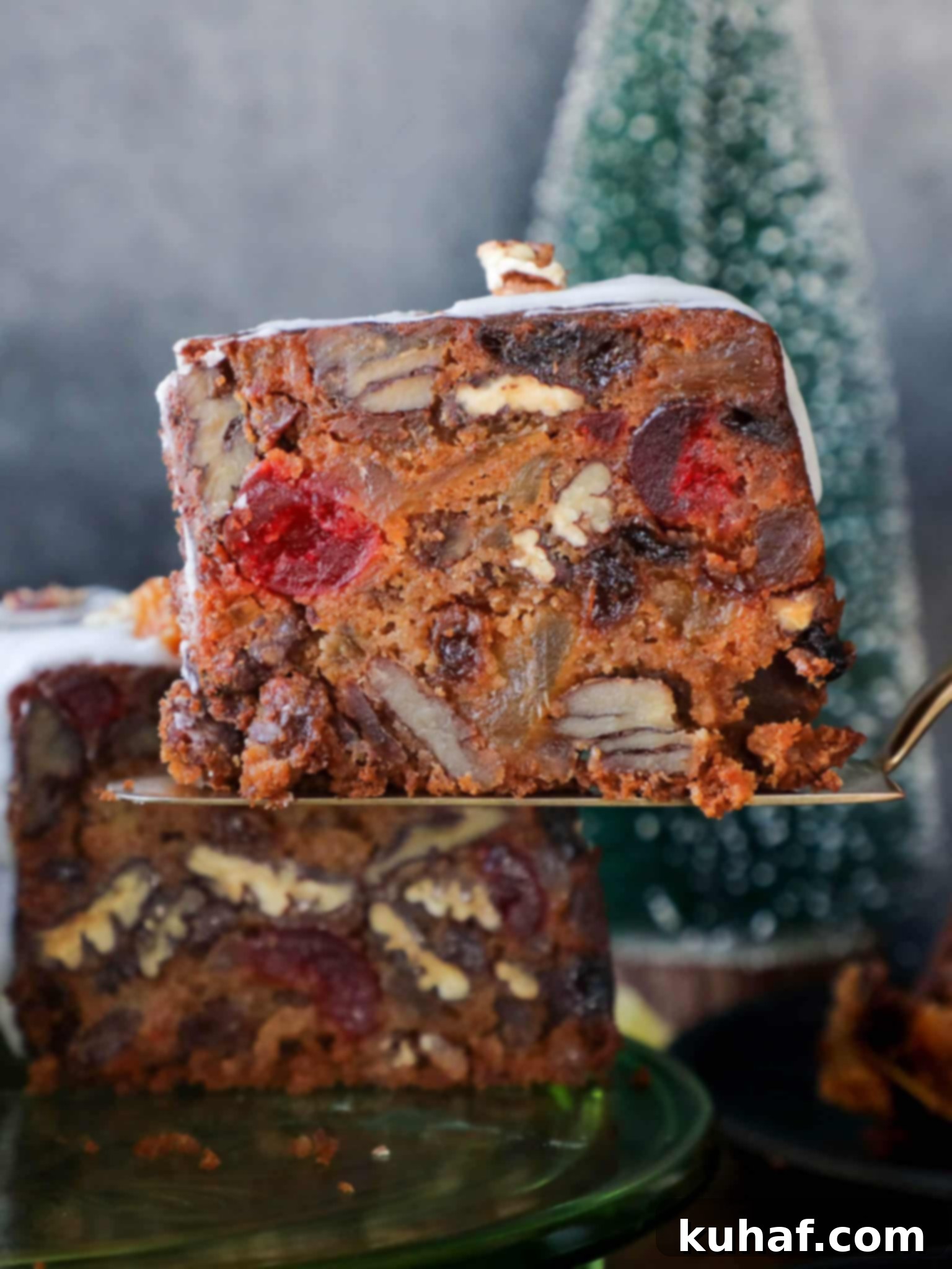 A slice of the moist fruit cake recipe beautifully presented on a cake server, revealing its rich interior with dried fruits and nuts.