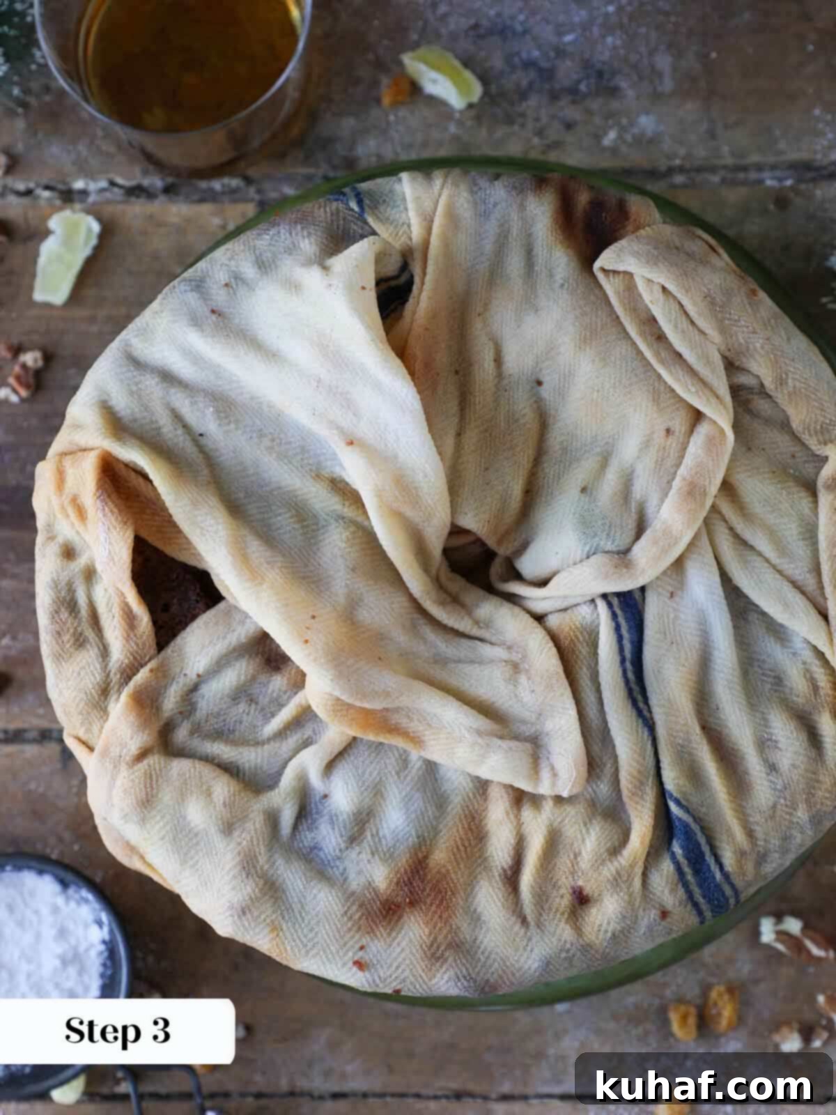 A fruit cake completely wrapped in a brandy-soaked towel, ready for the soaking process.