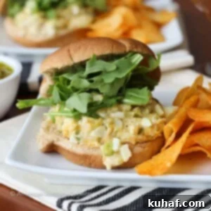 A close-up of a perfectly toasted tuna melt sandwich with melted cheese oozing out, resting on a cloth napkin.