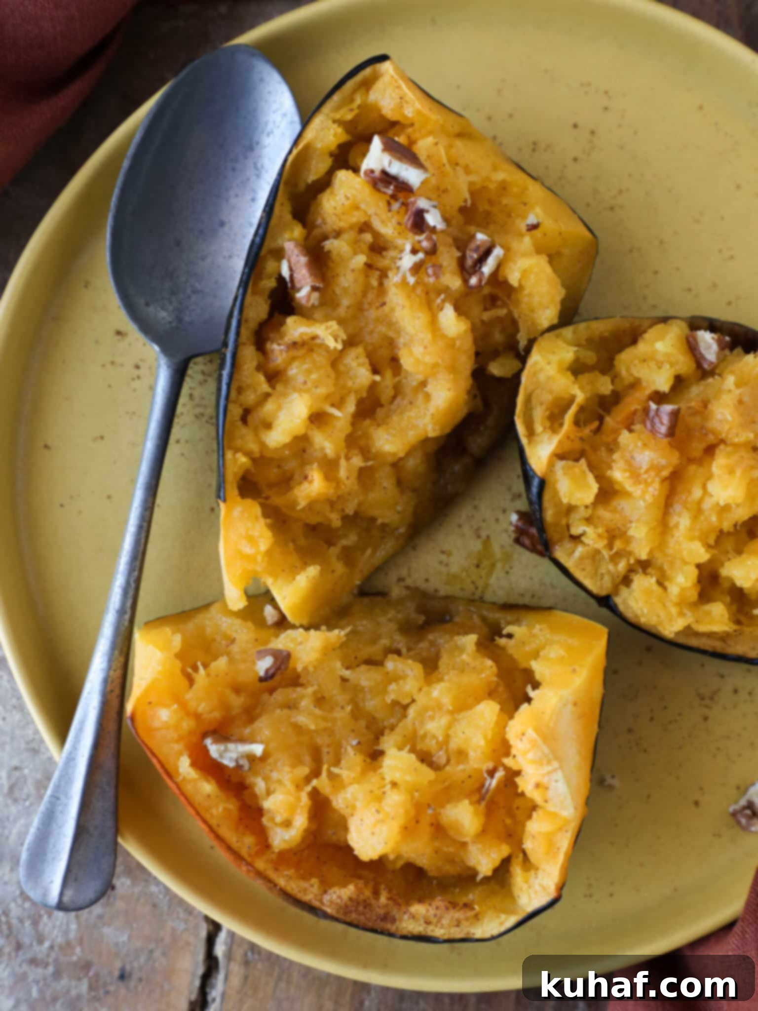 Brown Sugar Baked Acorn Squash Silver Spoon, a close-up of a perfectly baked acorn squash half with melted butter and brown sugar, ready to be served.