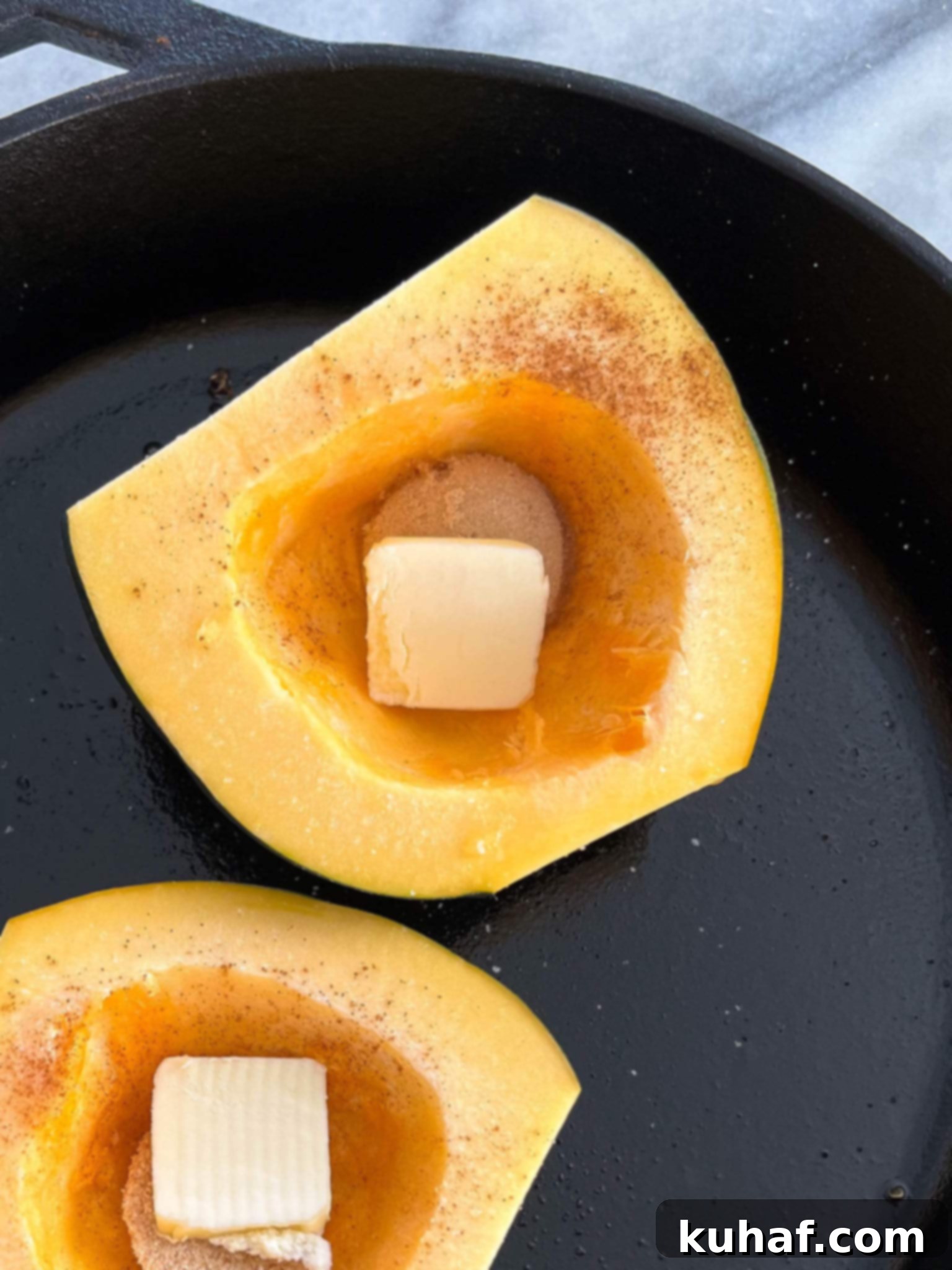 Brown Sugar Baked Acorn Squash Butter Cubes, showing two raw acorn squash halves with cubes of butter and brown sugar placed in their centers, ready for baking.