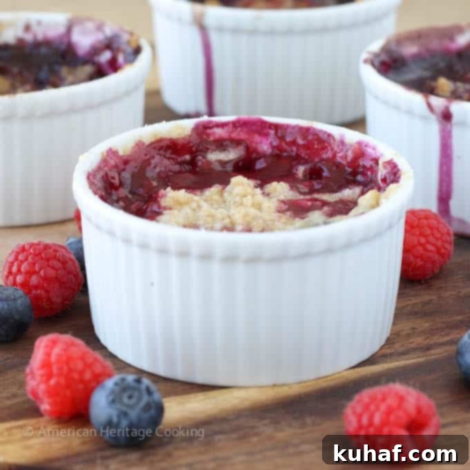 Two individual blueberry raspberry crumbles on a white plate, showcasing the crispy topping and bubbly filling.