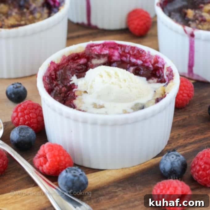 Close-up of a warm individual blueberry raspberry crumble with the fruit filling bubbling up through the topping.