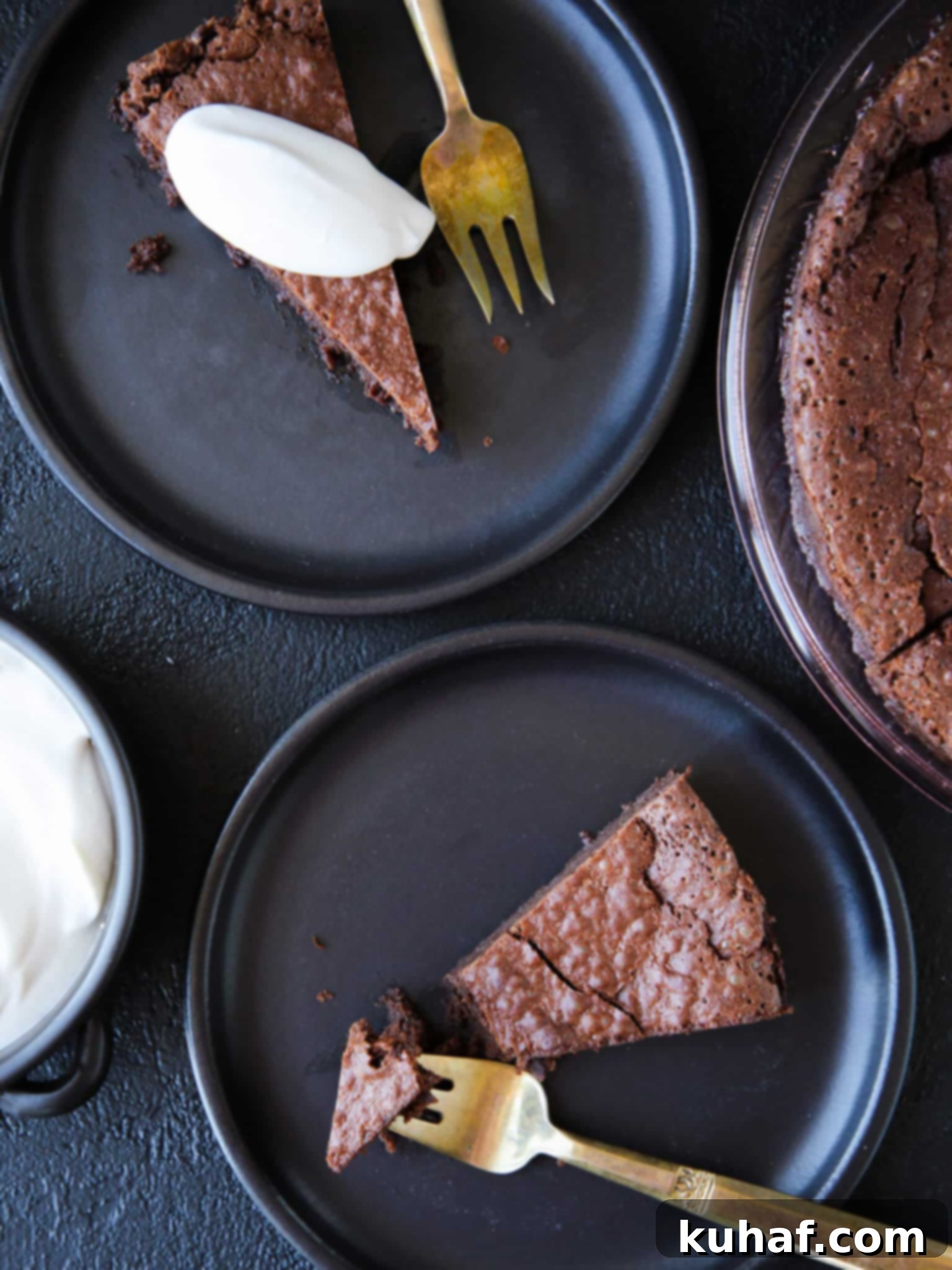 Romantic Valentine's Desserts 2 Flourless Chocolate Decadence Cake slices on black plates with whipped cream, perfect for Valentine's Day.