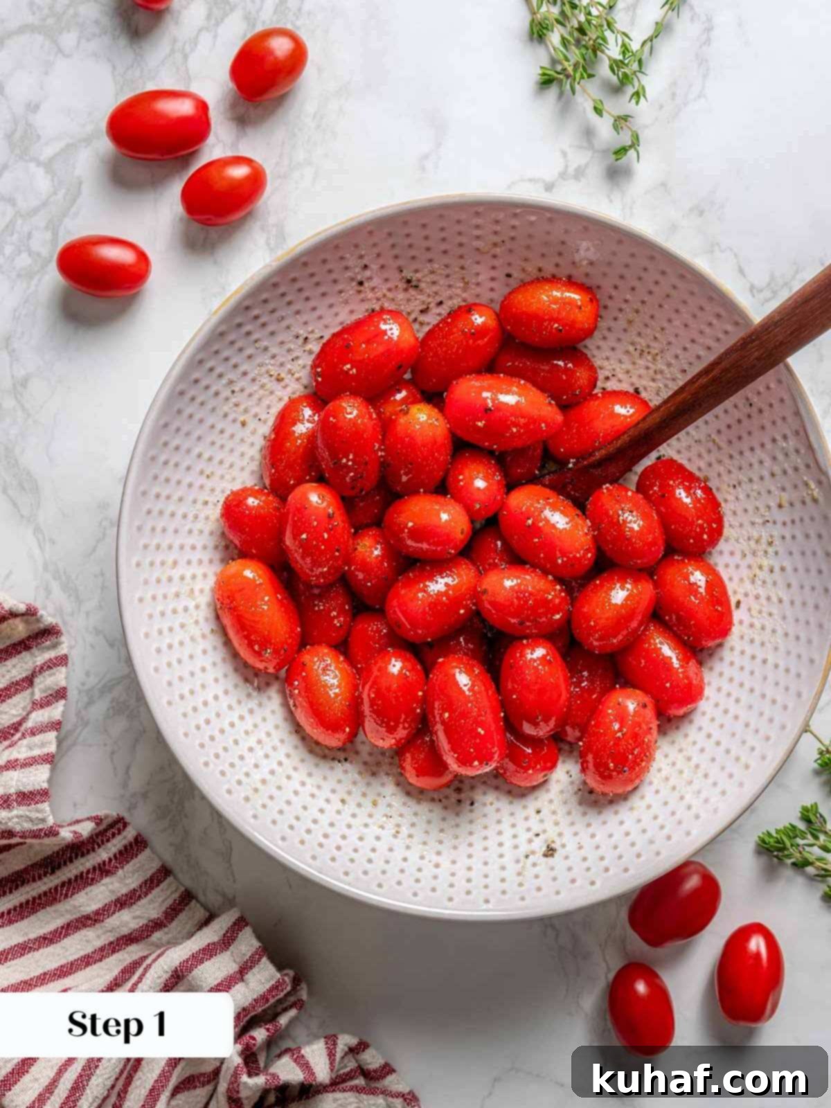 Bright red cherry tomatoes glistening with olive oil and seasoning in a bowl, ready for slow roasting, promising sweet concentrated flavor.