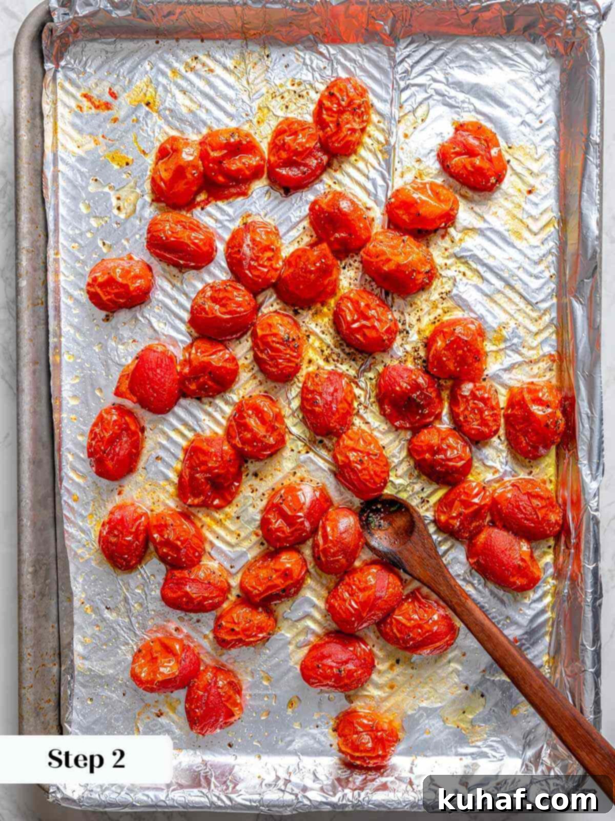 A baking sheet lined with foil, laden with perfectly slow-roasted tomatoes, tender and bursting with flavor, cooling after their long oven bath.
