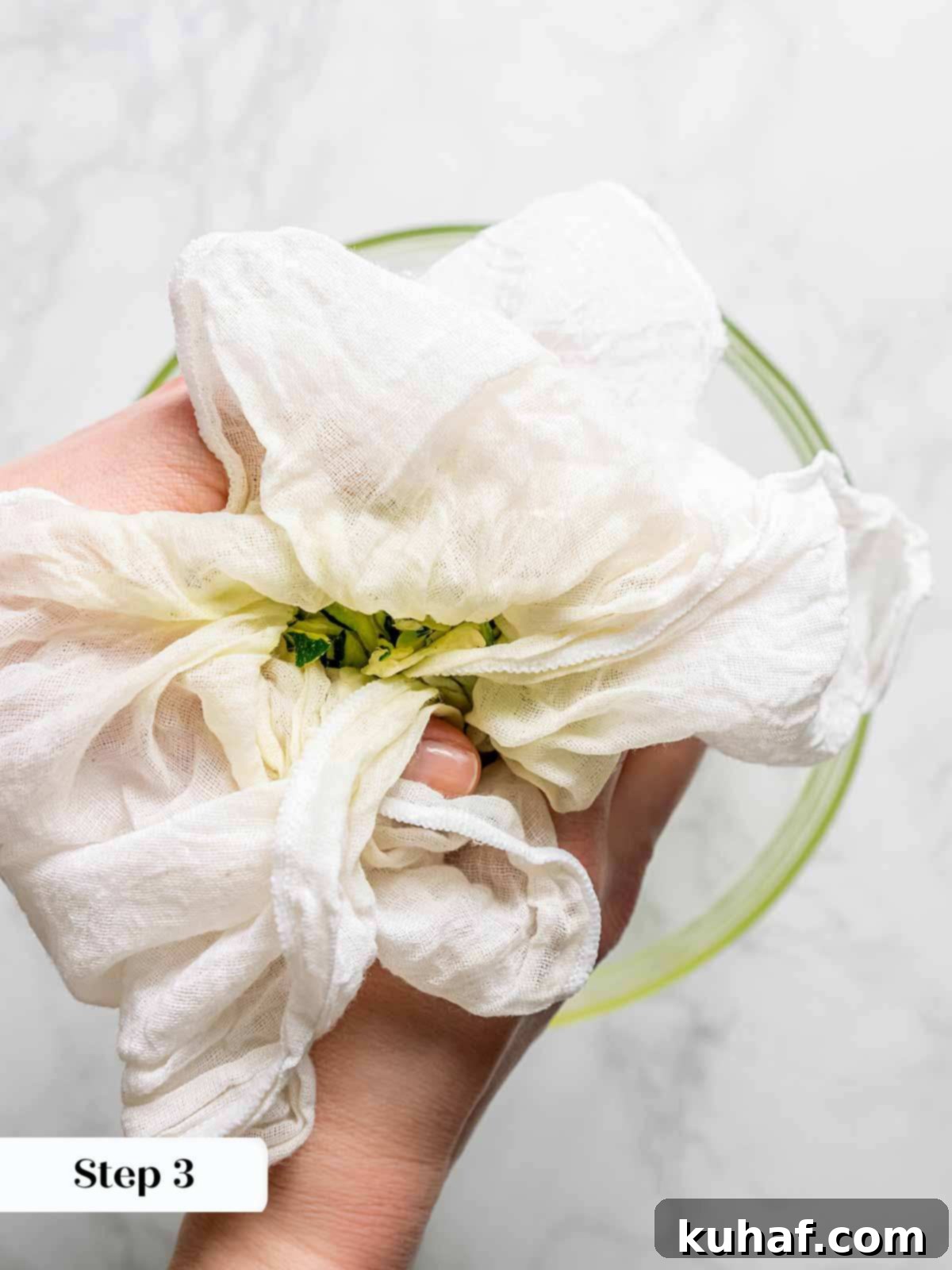 Close-up of shredded zucchini being vigorously squeezed in a cheesecloth, showing the release of excess liquid—a crucial step for crispy fritters.