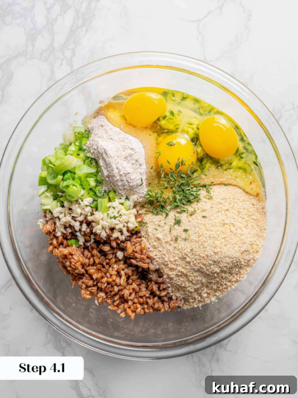 A large bowl filled with uncooked zucchini fritter ingredients—shredded zucchini, farro, breadcrumbs, and herbs—before being mixed, showcasing the fresh components.