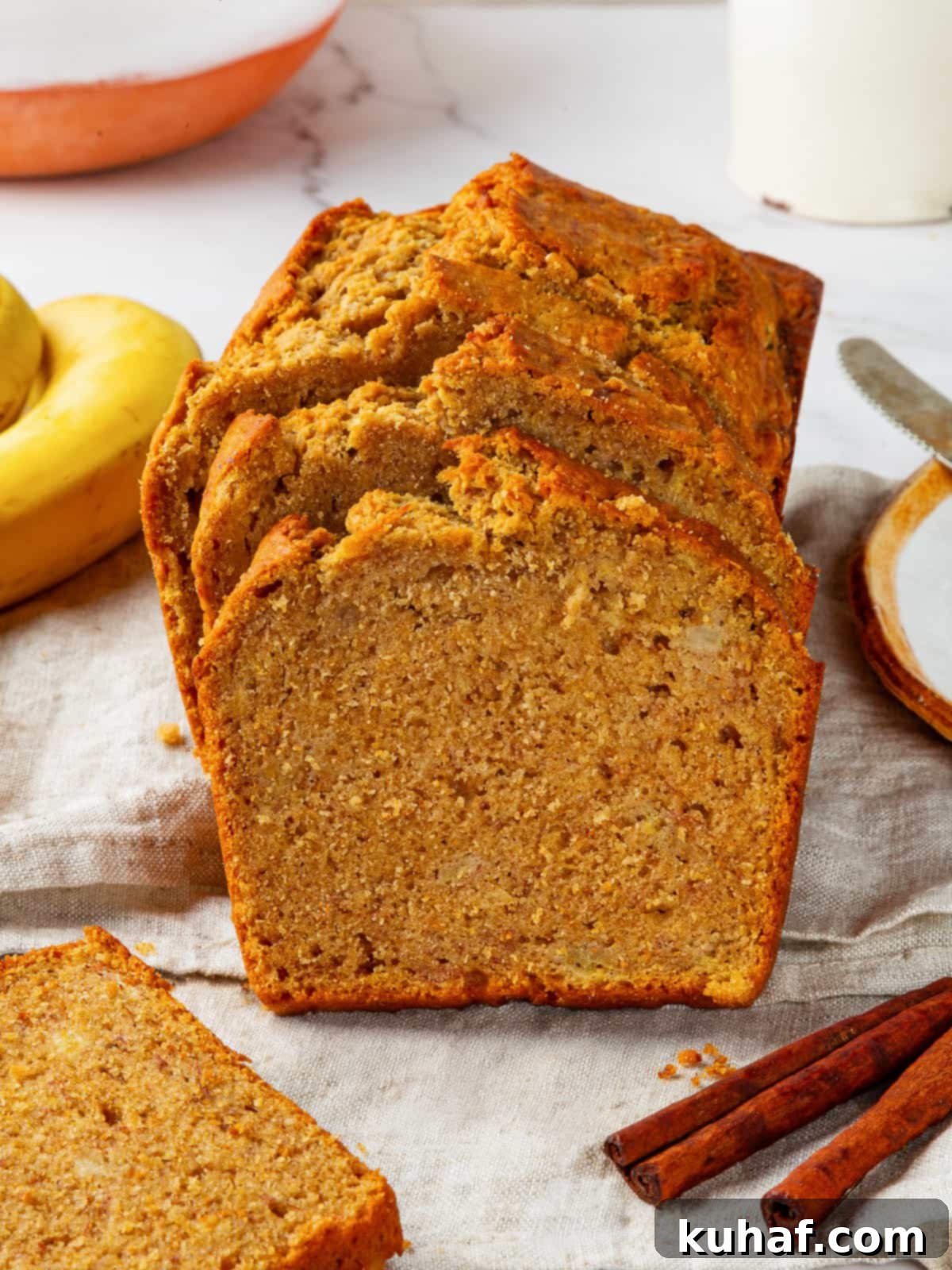 A freshly baked loaf of pumpkin banana bread resting on a white towel, showcasing its golden-brown crust and inviting texture.