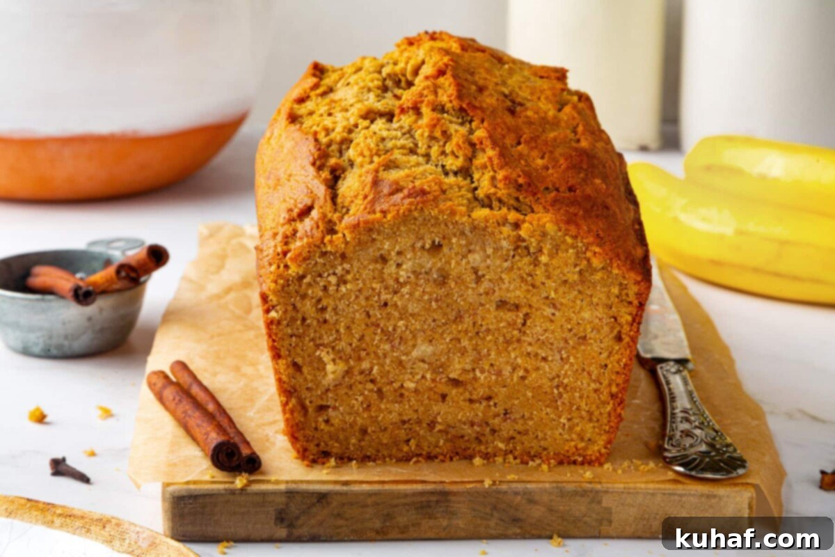 A beautifully sliced loaf of pumpkin banana bread arranged on a rustic wooden cutting board, ready for serving, highlighting its tender crumb and spiced aroma.