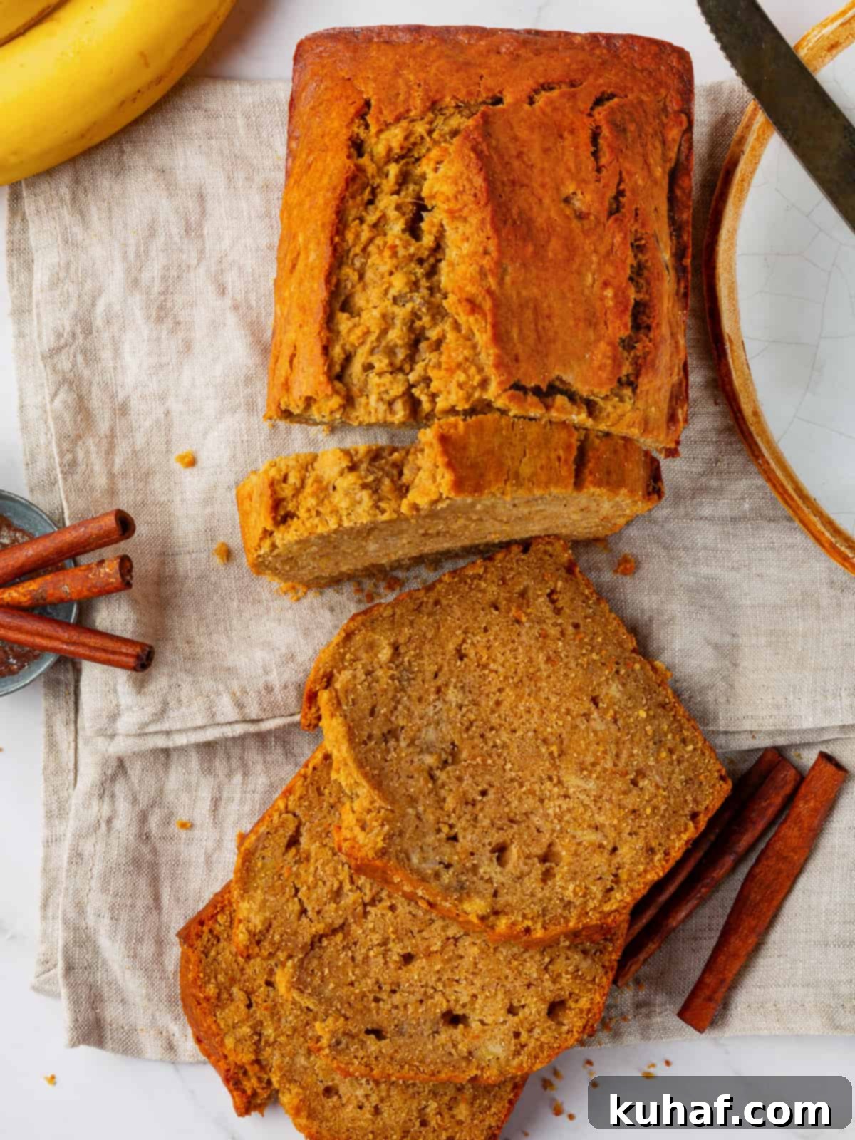 A perfectly baked loaf of pumpkin banana bread, just out of the oven, showcasing its irresistible golden-brown crust and filling the kitchen with a wonderful spiced aroma.