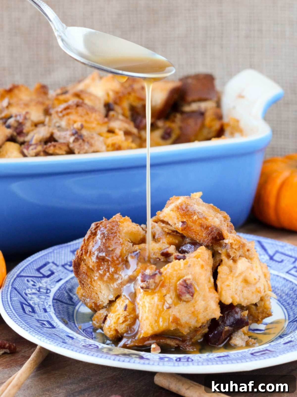 Pumpkin bread pudding with maple bourbon sauce pouring over it.