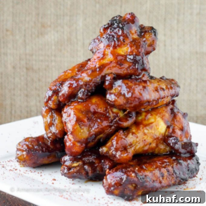 A pile of perfectly baked chicken wings, generously coated in a thick, glossy chipotle maple sauce, ready to be served.