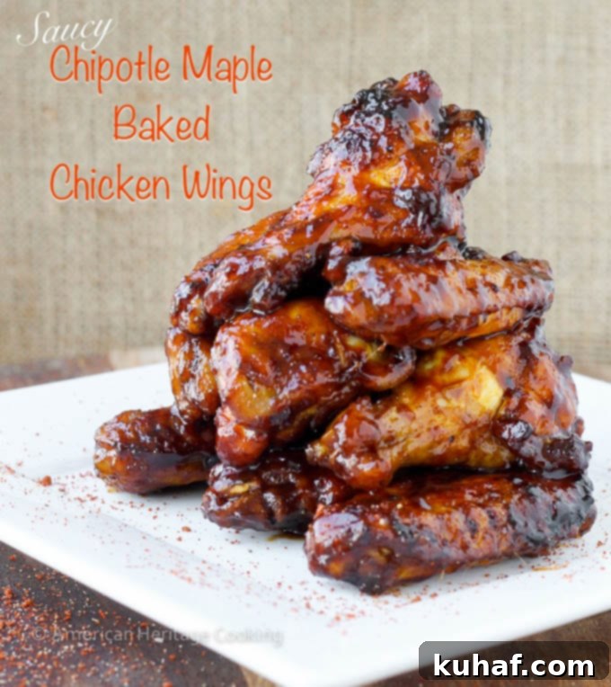 A pile of chicken wings after being baked and seasoned with a dry rub, with extra chili powder on a white plate.