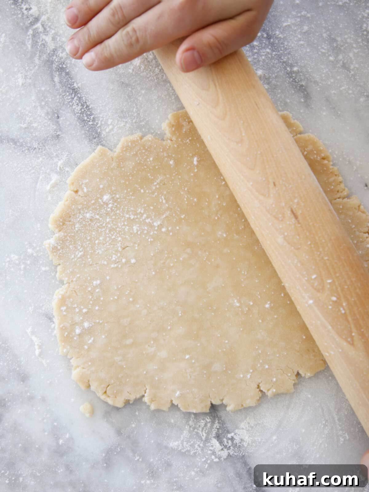 Crisco pie crust being rolled with a rolling pin on a baking surface.