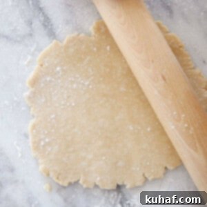 Crisco pie dough rolled on marble surface with a rolling pin.