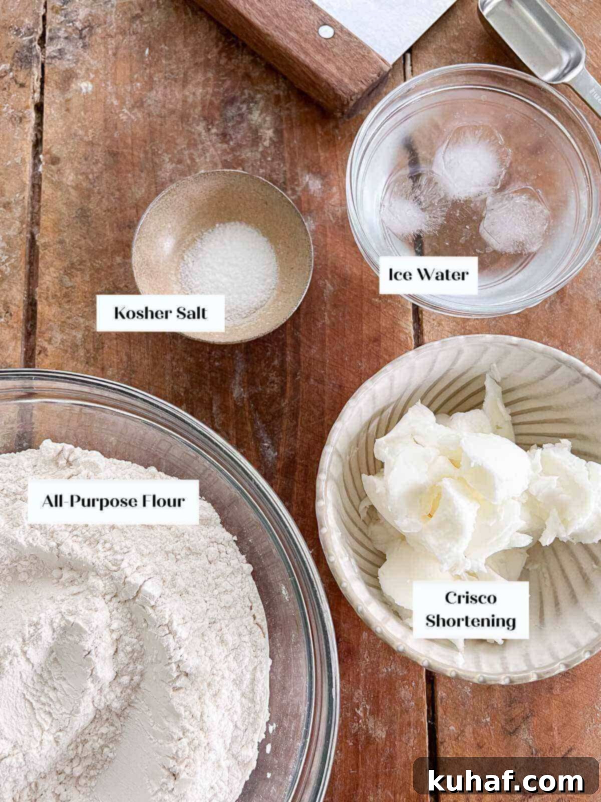 Crisco pie crust ingredients laid out on a wooden surface, including flour, salt, shortening, and water.