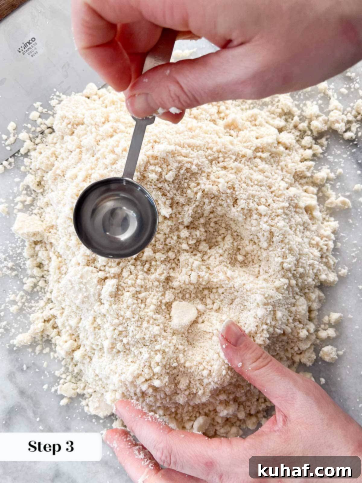 Adding water by the teaspoon to pie crust dough mixture.