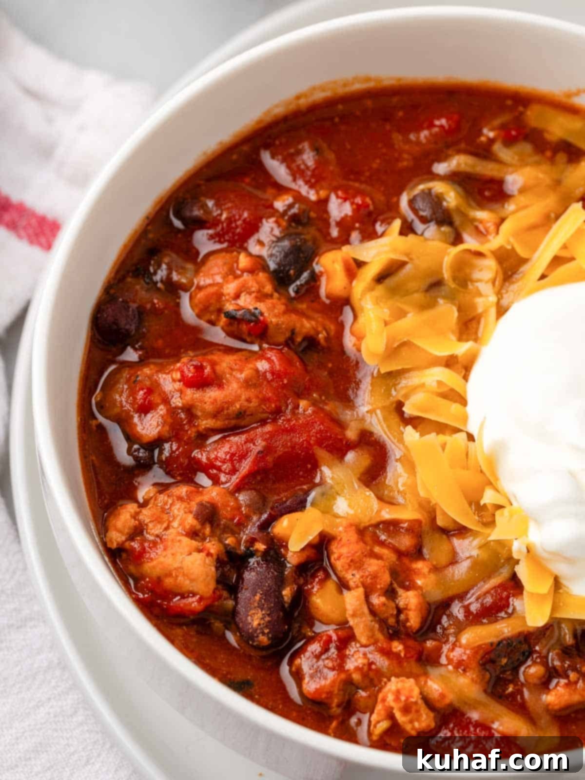 Smoky Chipotle Heat 2 A hearty bowl of smoky chipotle chili with beans, garnished with a dollop of sour cream and shredded cheese.