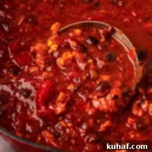 Smoky Chipotle Heat 10 A ladle full of rich, smoky chipotle chili, ready to be served from a large pot.