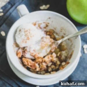 Individual serving of Microwave Apple Crisp in a bowl, topped with a dollop of cream.