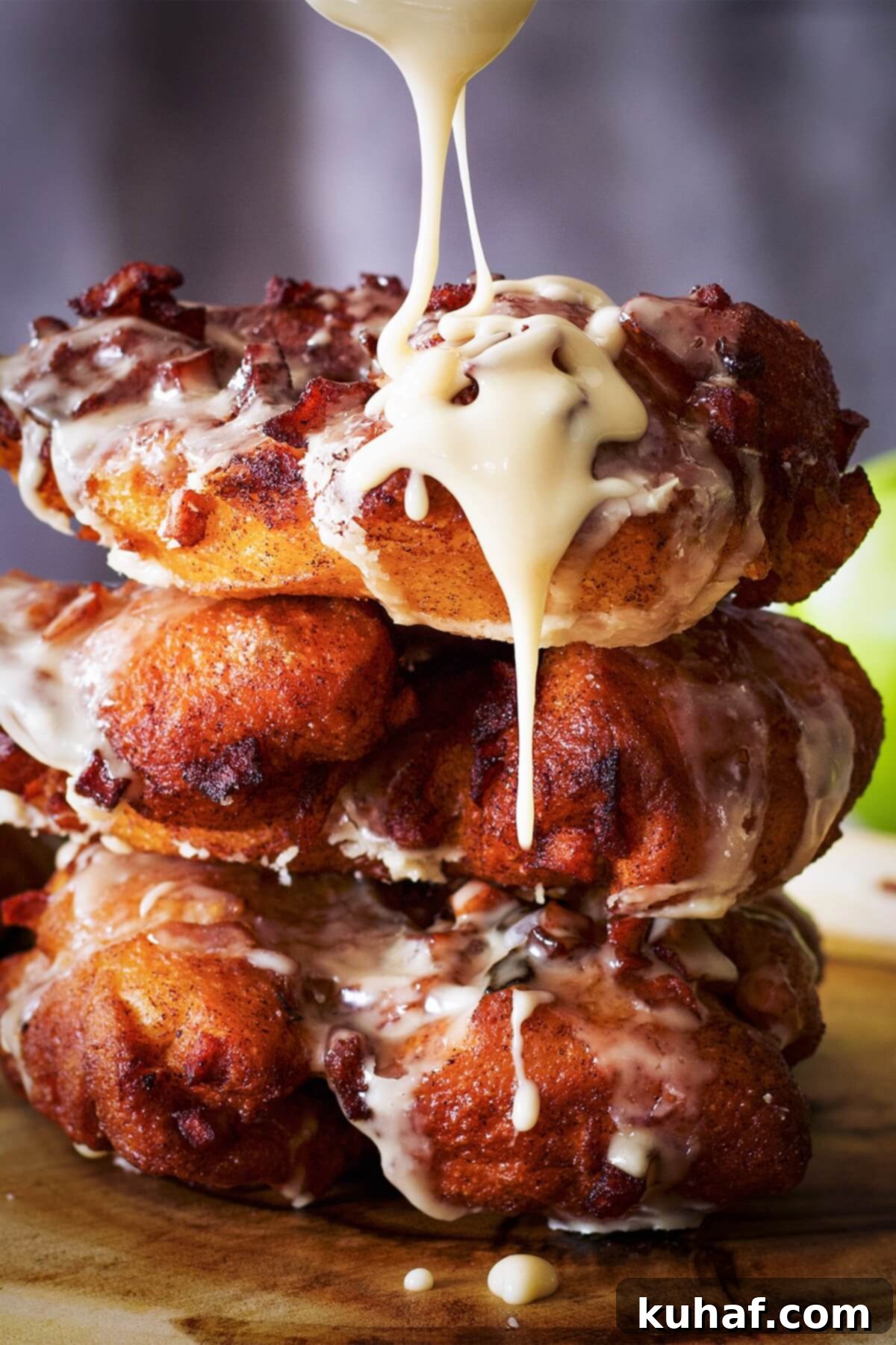 A stack of perfectly fried apple fritters, generously drizzled with a sweet maple glaze.