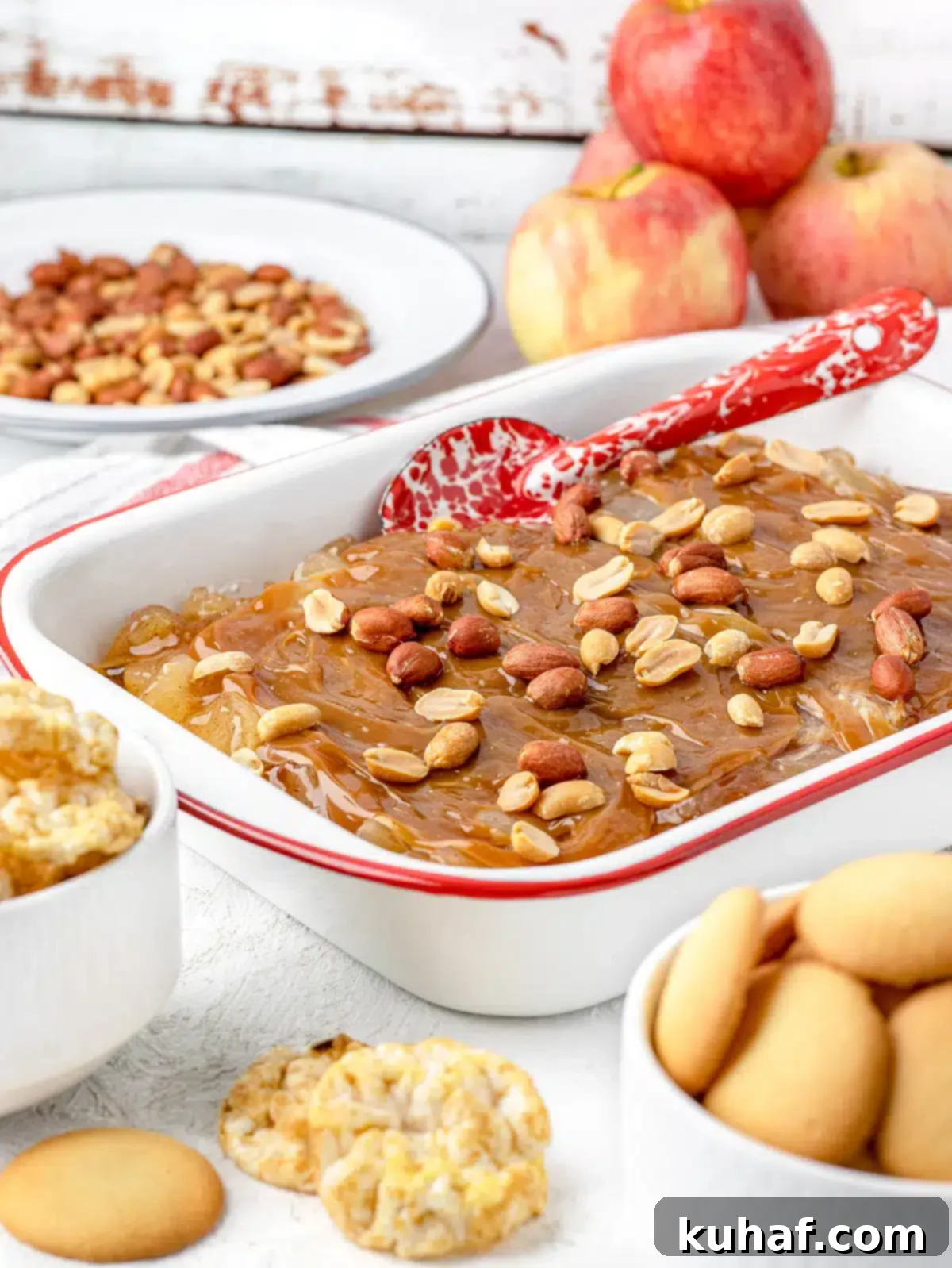 Decadent caramel apple pie dip in a bowl, surrounded by apple slices and graham crackers for dipping.