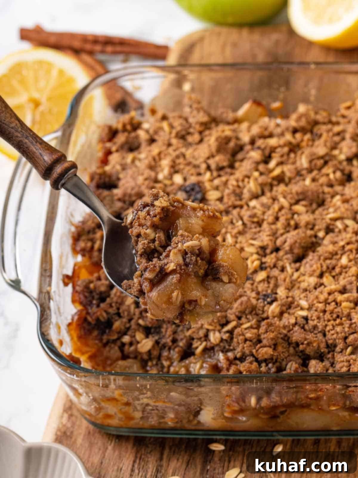 A large spoon scooping a portion of warm, baked apple crisp, highlighting the golden topping and tender apple filling.
