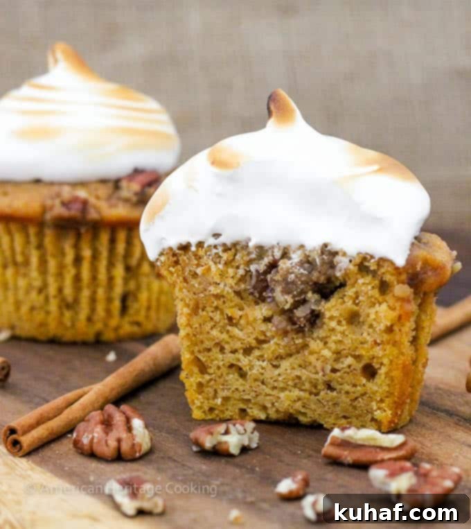 A close-up of a Sweet Potato Casserole Cupcake, showing the intricate layers of cake, pecan topping, and torched marshmallow.