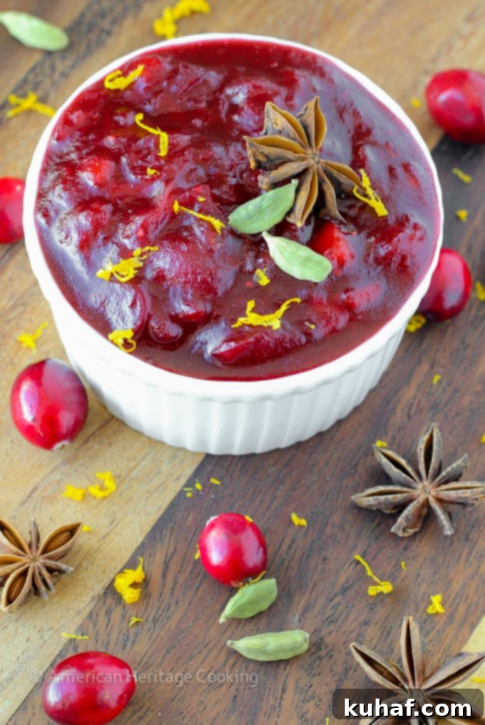 Homemade Spiced Apple Cider Cranberry Sauce in a beautiful serving bowl, garnished with fresh cranberries.
