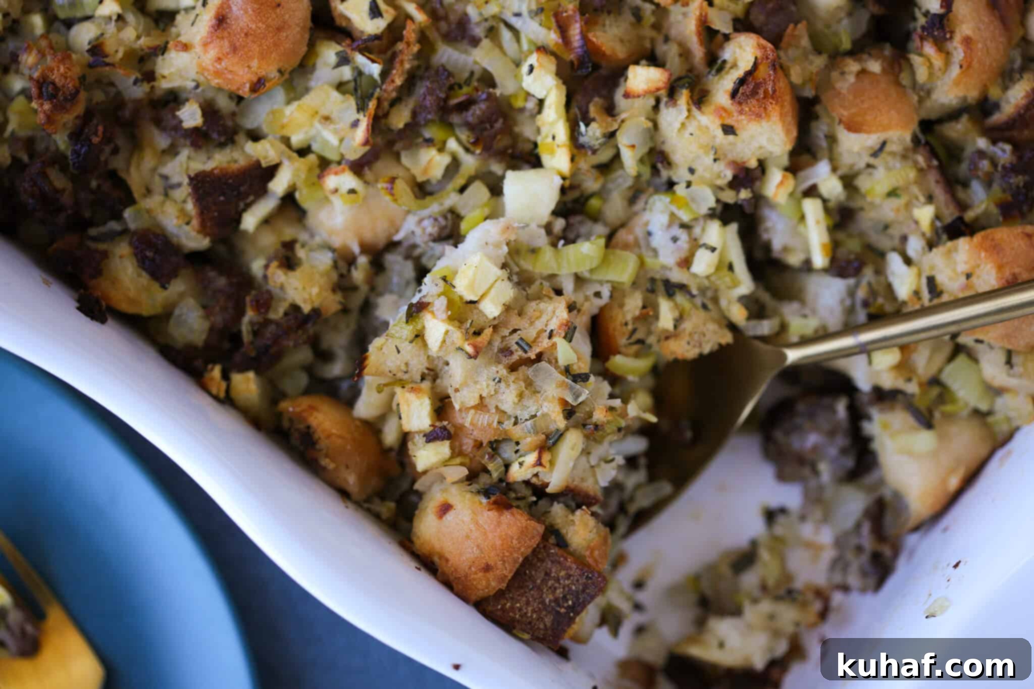 Close-up of Apple Sage Sausage Stuffing in a white baking dish with a beautifully toasty, crusty bread top.