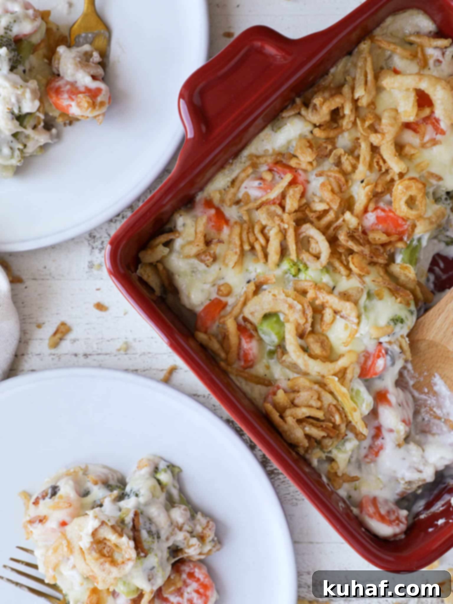 Garden Harvest Casserole 2 A vibrant vegetable casserole, golden brown and bubbly, served in a red baking dish. Two white plates are ready for serving, highlighting its comfort food appeal.
