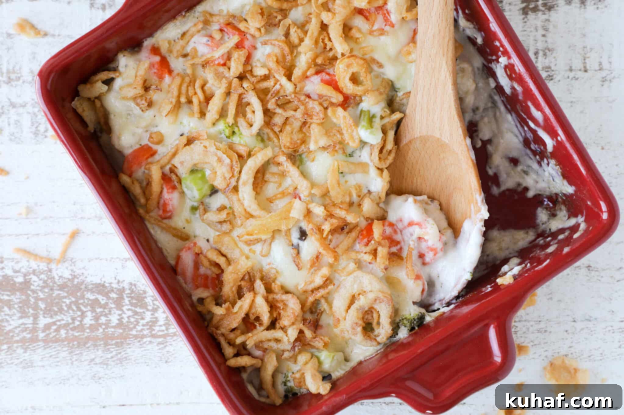 Garden Harvest Casserole 4 A close-up of a golden-brown, baked vegetable casserole in a rustic red dish, topped with crispy fried onions, fresh from the oven and ready to serve.
