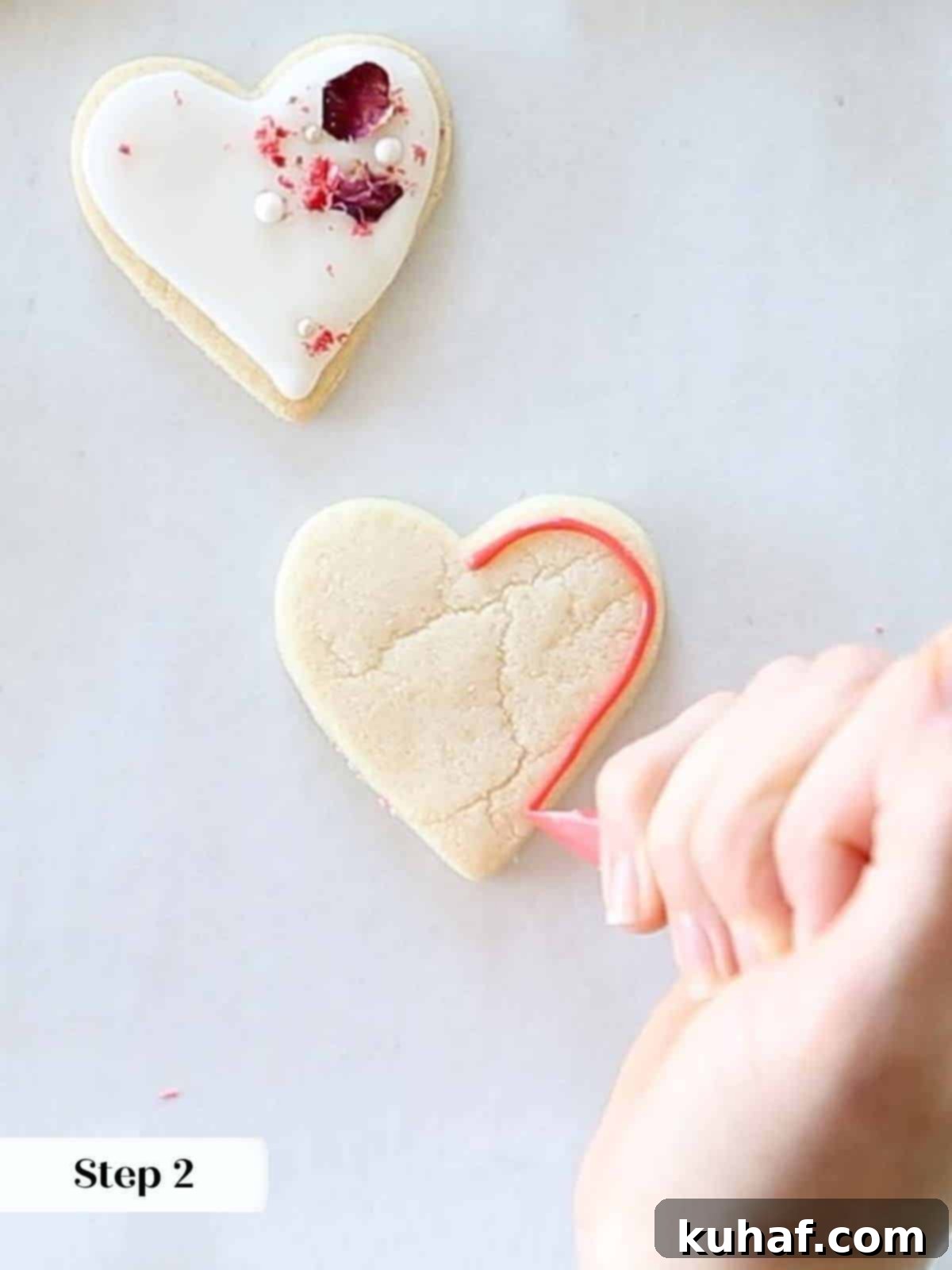 Carefully outlining a heart-shaped sugar cookie with vibrant red royal icing, creating a barrier for flooding.