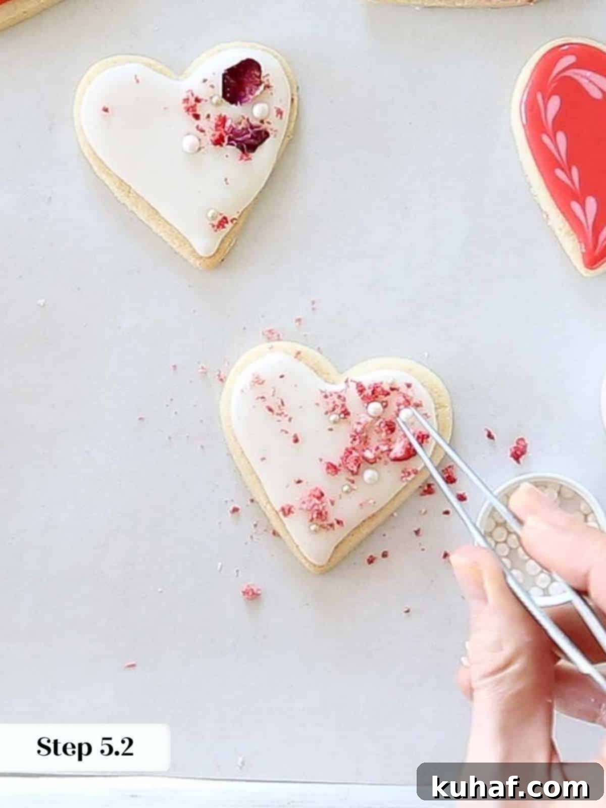 Adding elegant sugar pearls to white royal icing on heart-shaped sugar cookies, enhancing their festive appeal.