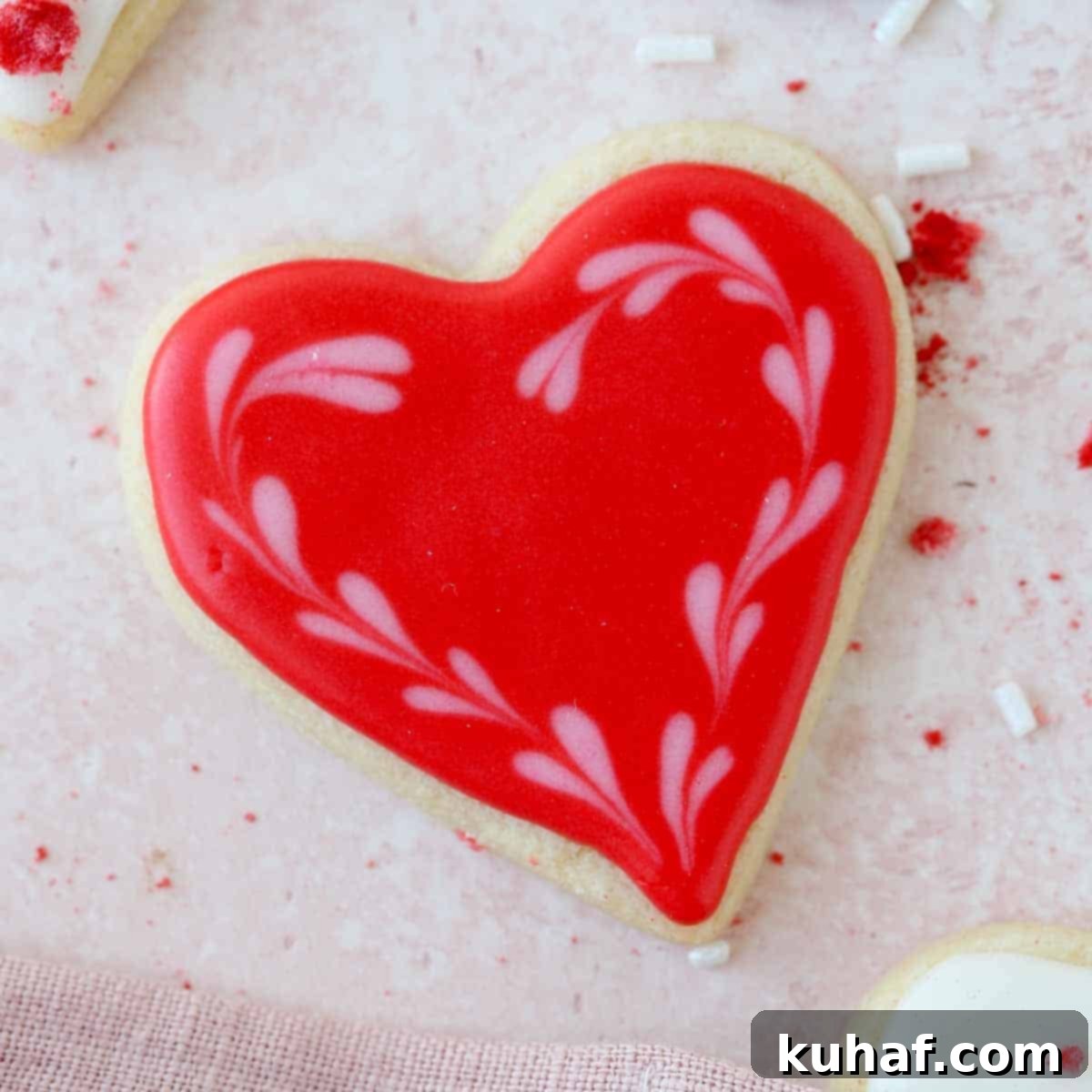 A single red heart decorated sugar cookie showcasing a vibrant, smooth royal icing finish, ready to be enjoyed.