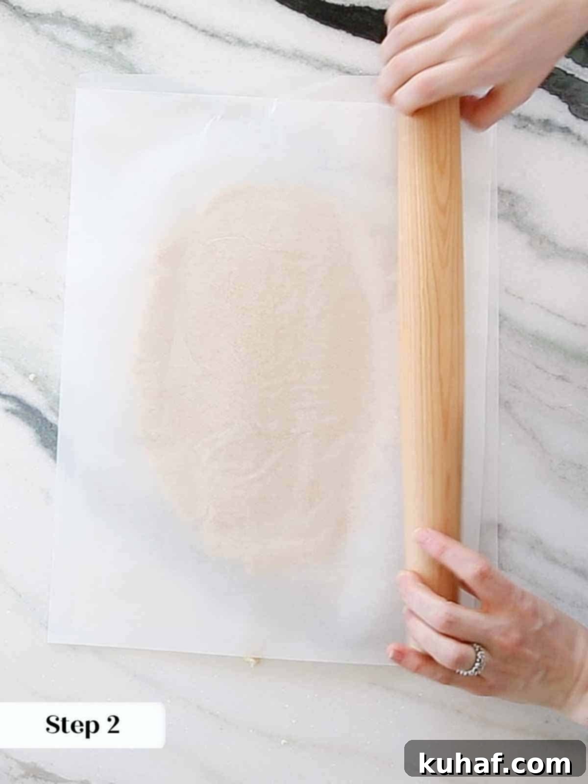 Rolling sugar cookie dough evenly between two sheets of parchment paper for consistent thickness and easy handling.