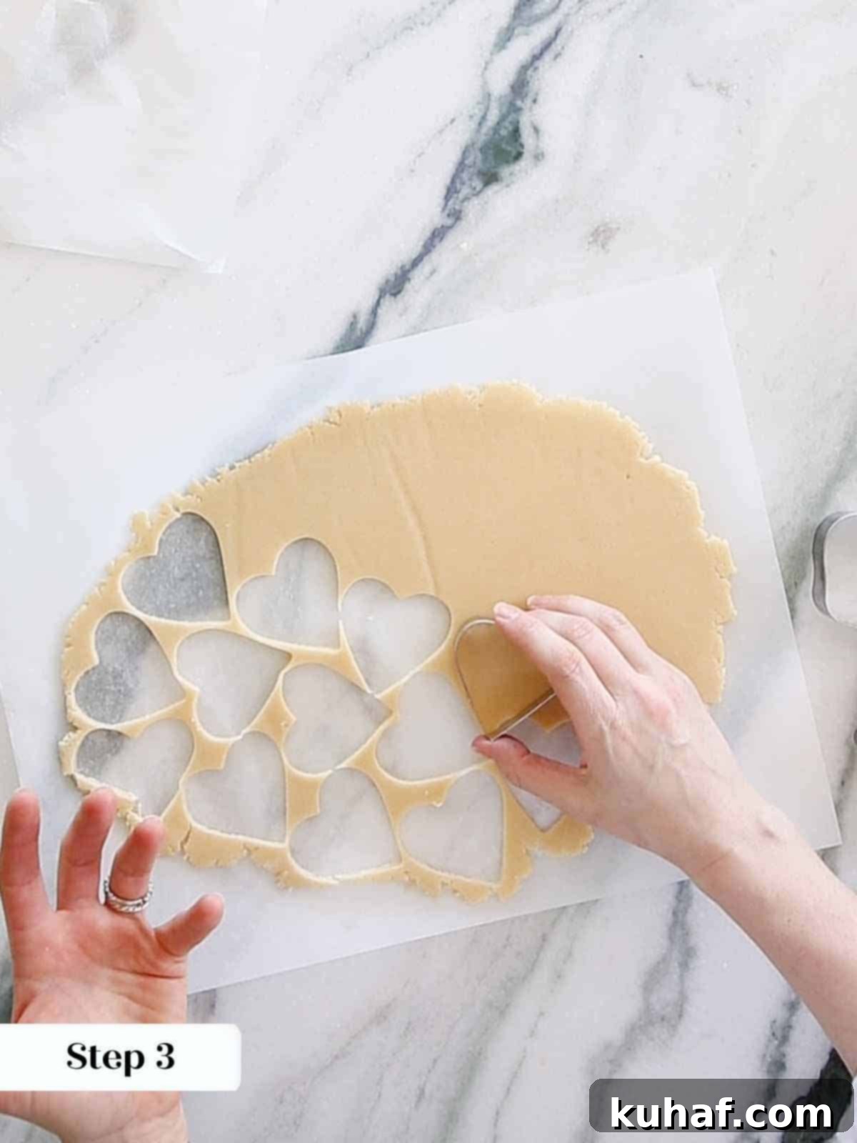 Using a heart-shaped cookie cutter to neatly cut out cookie dough, preparing for baking.