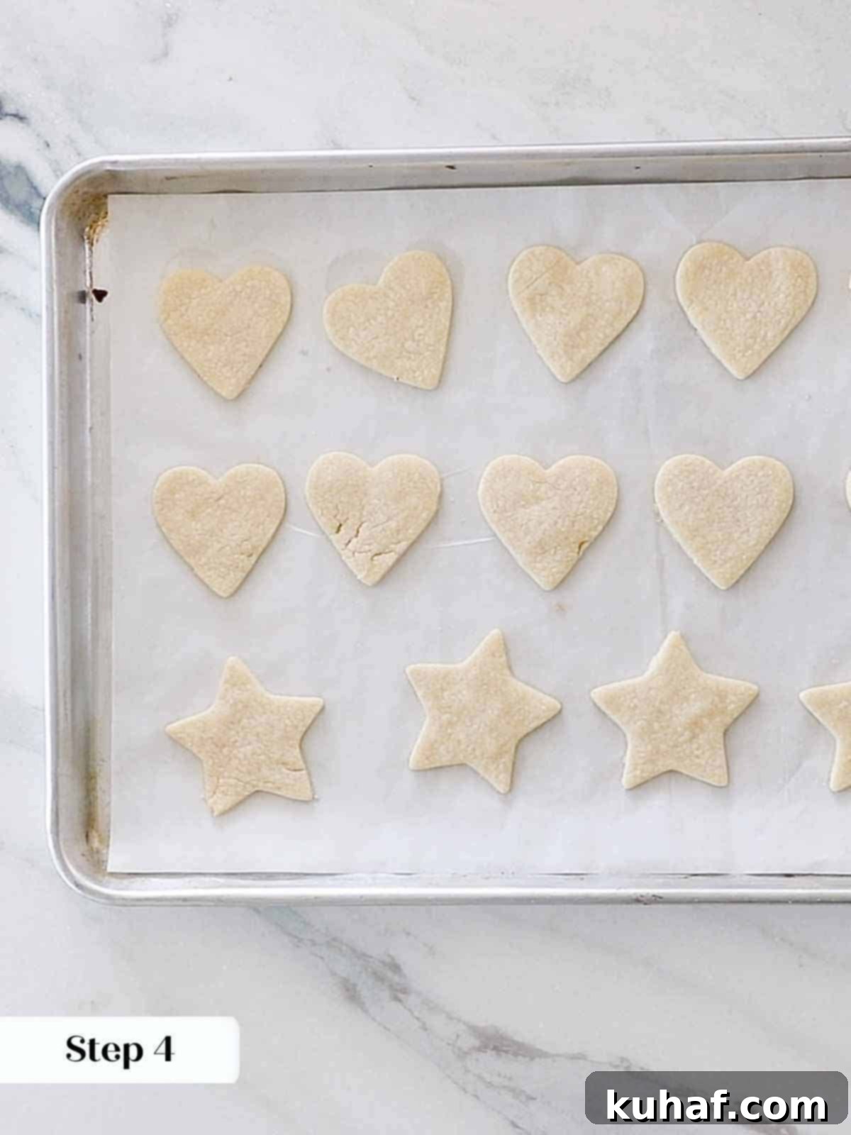 Freshly baked heart-shaped sugar cookies cooling on a baking sheet, with perfect, defined edges.