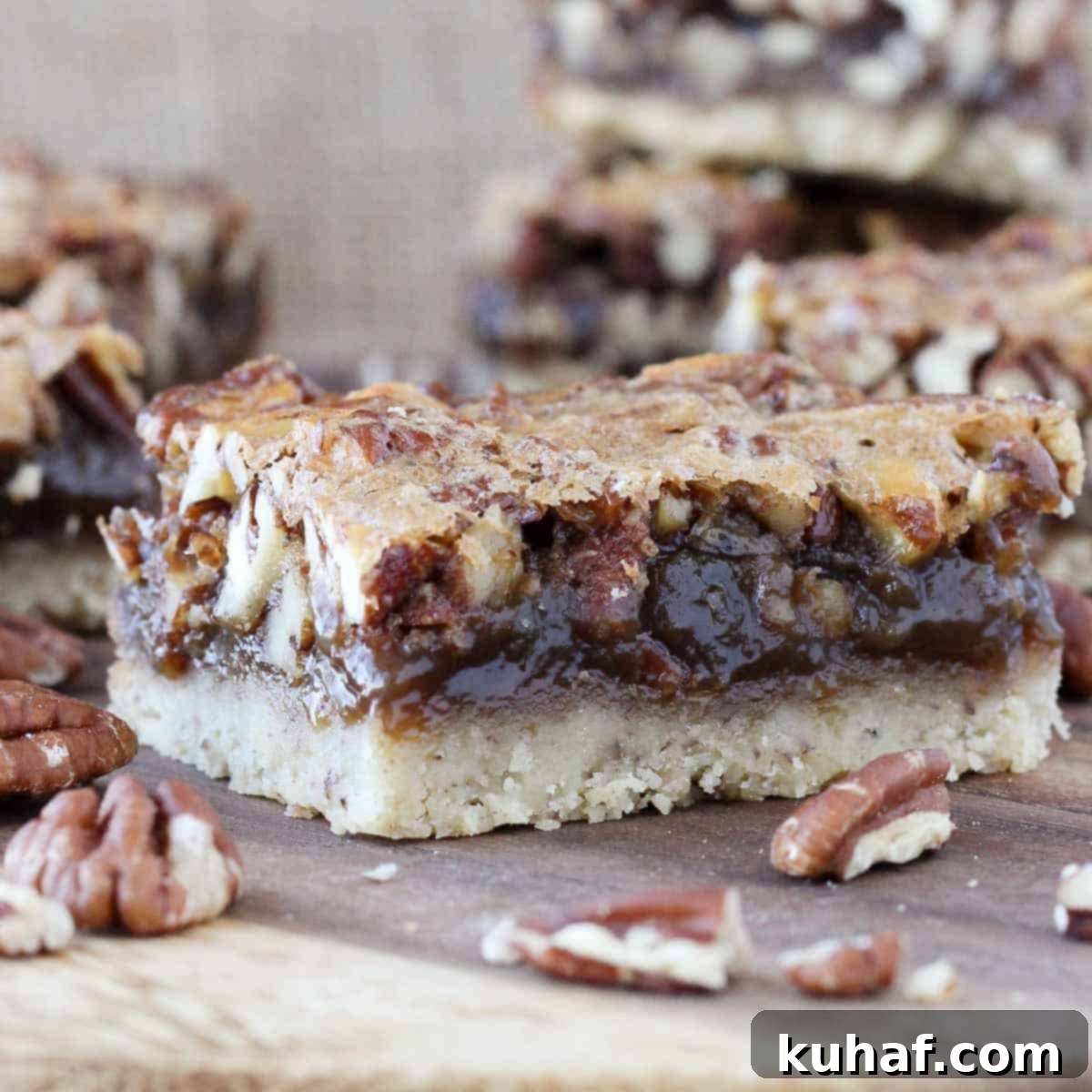 A perfectly cut square of pecan pie bar resting on a rustic wooden board, ready to be enjoyed. The rich, golden brown color and the visible pecan pieces are enticing.