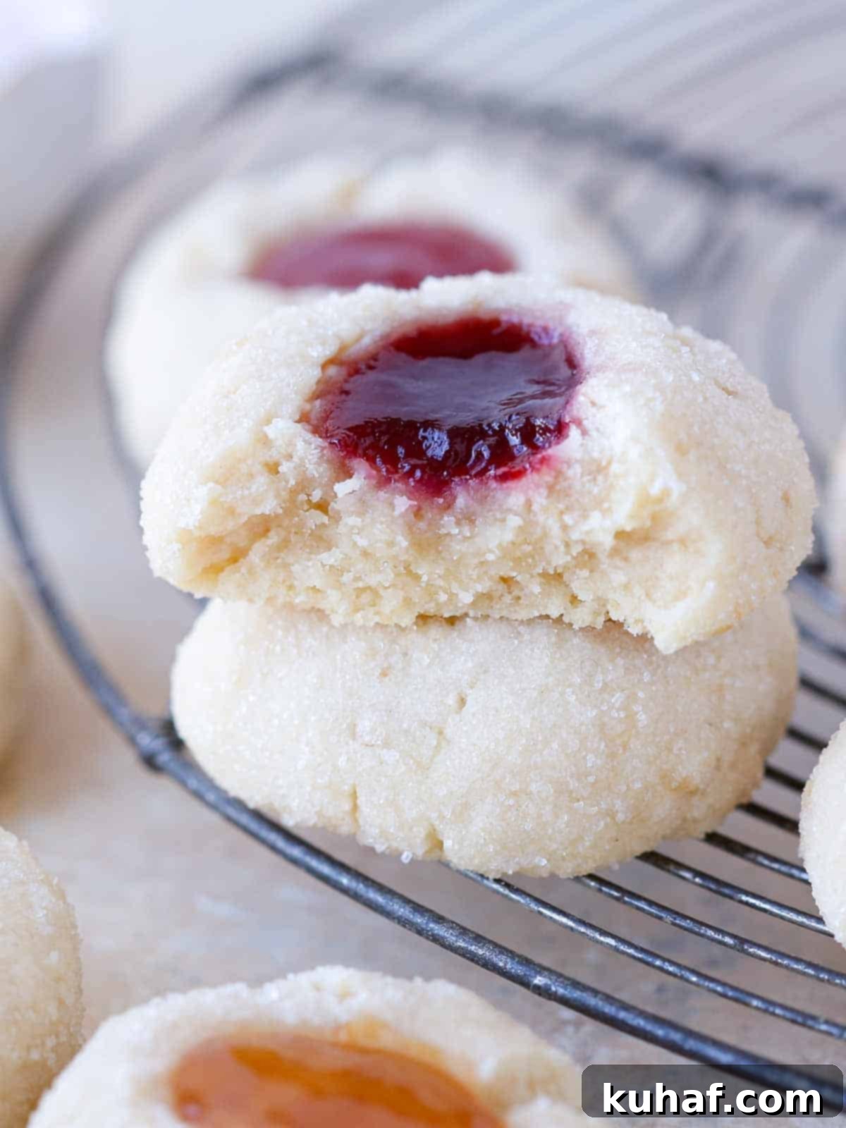 Close-up of a broken thumbprint cookie on a wire rack, showing its tender, crumbly texture.