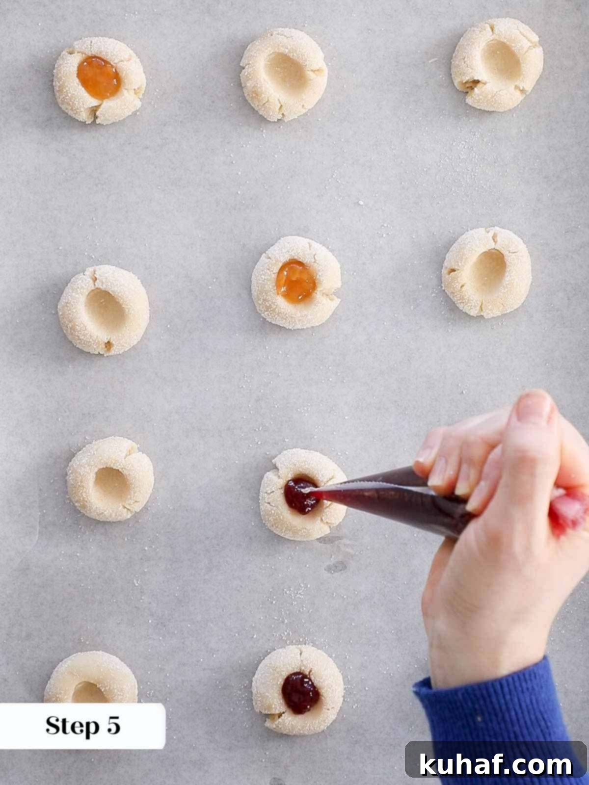 Filling thumbprint cookie indentations with jam before baking.