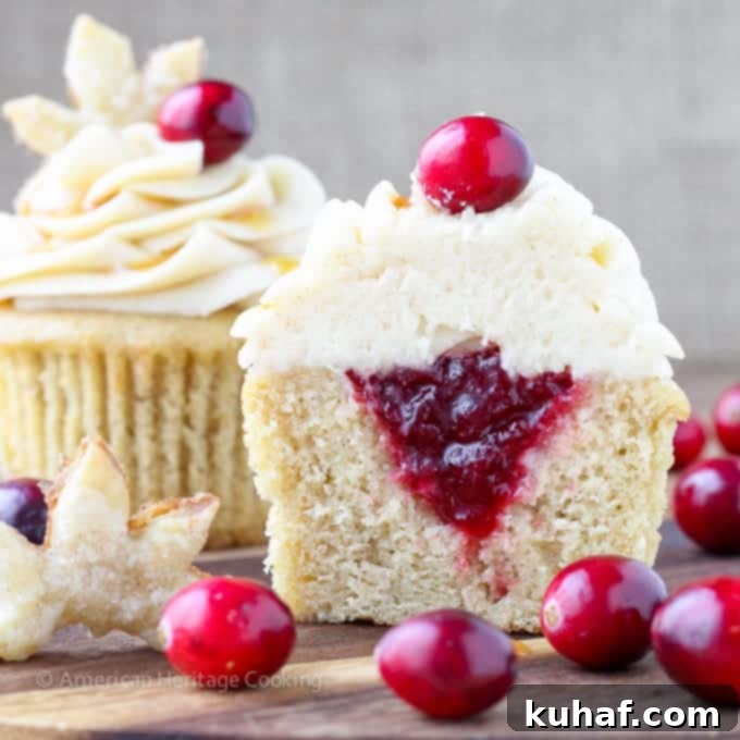 Close-up of a filled Apple Cider Cranberry Cupcake with a cutout showing the delicious cranberry sauce compote inside.