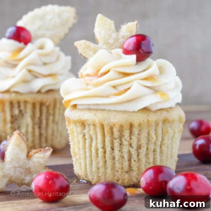Beautifully piped cinnamon cream cheese frosting on a Spiced Apple Cider Cranberry Cupcake, adorned with a pie crust leaf and an apple cider reduction drizzle.