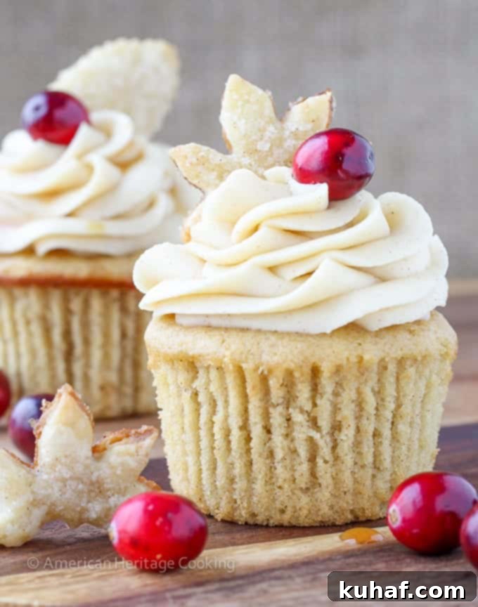 Vertical shot of several Spiced Apple Cider Cranberry Cupcakes showcasing their intricate details, frosting swirls, and festive charm.