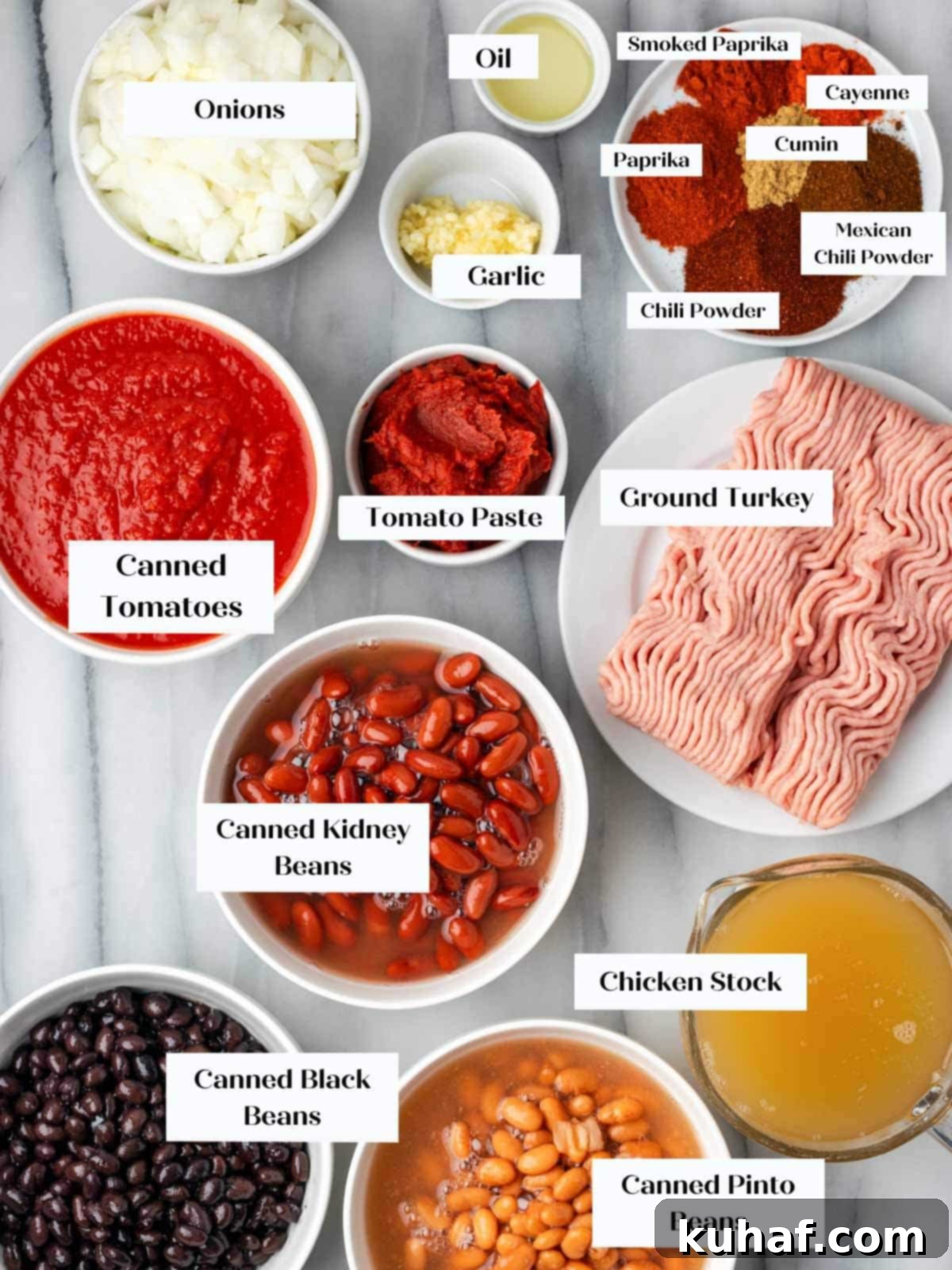Various ingredients for turkey chili laid out on a marble surface.