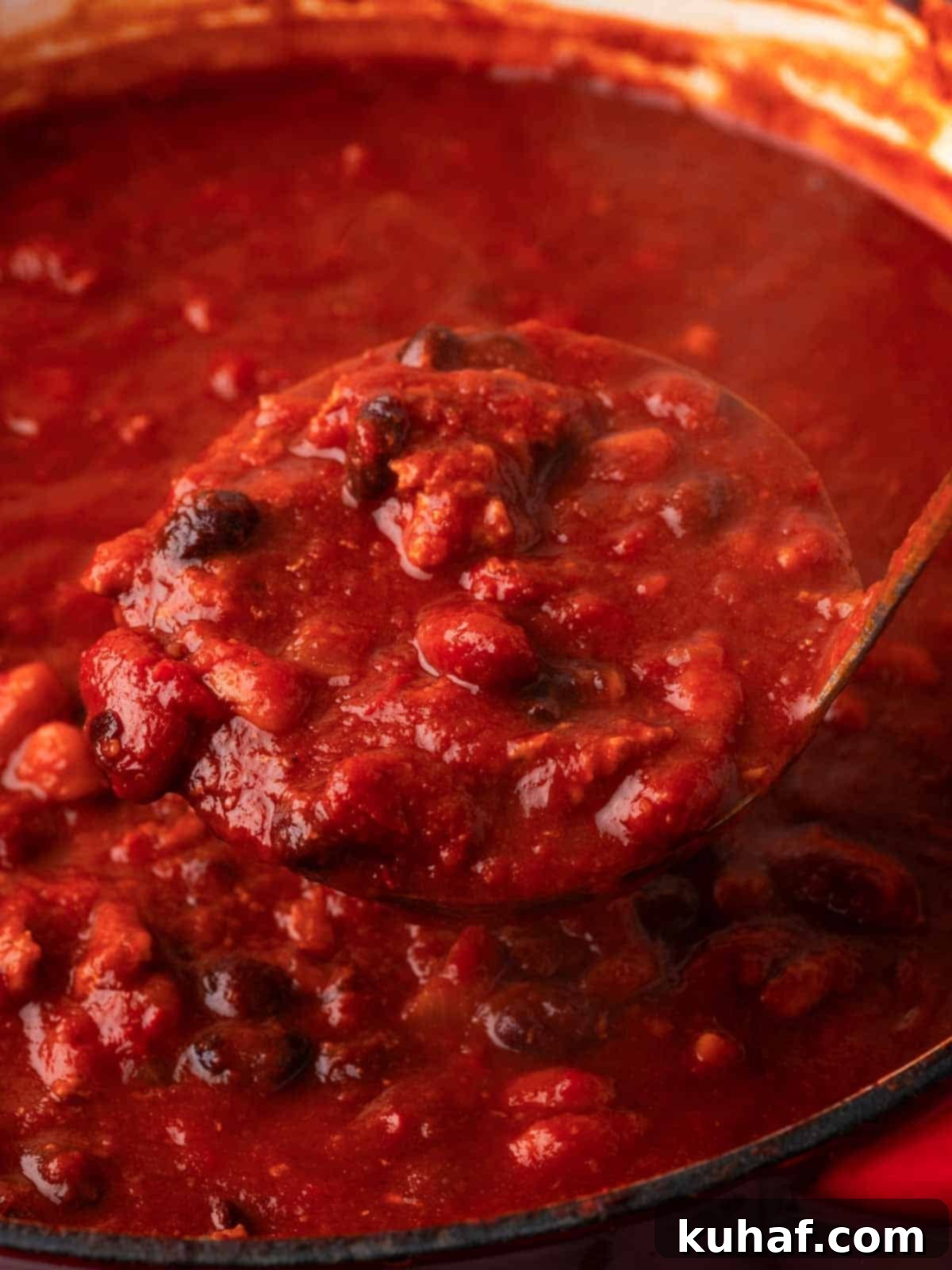 Scooping rich turkey chili from a Dutch oven with a ladle.