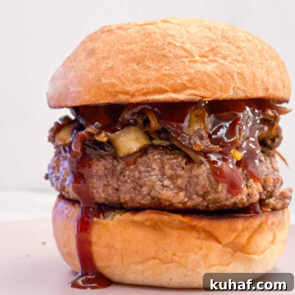 A mouth-watering burger with homemade BBQ sauce generously dripping down, served on a fresh bun with toppings.
