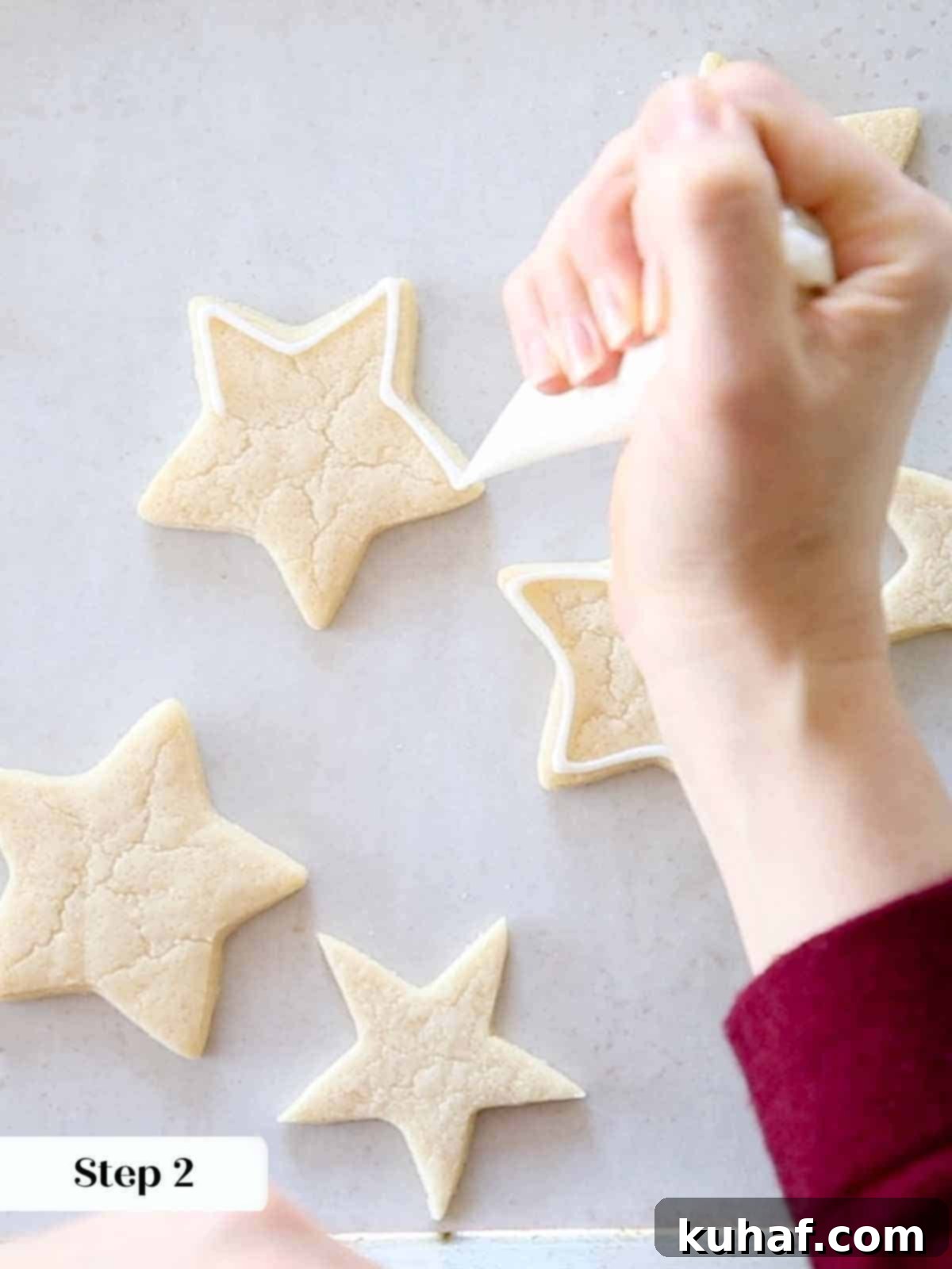 outlining white royal icing on sugar cookie stars.